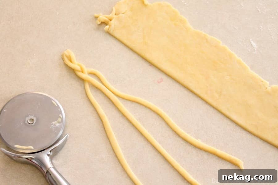 Thin strips of pie crust being braided on a counter, demonstrating the technique for creating a decorative edge.