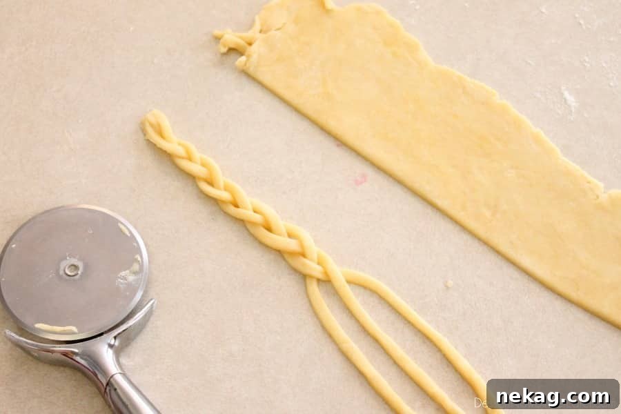 The braiding technique close-up, showing three strands of pie dough being intertwined to form a braid.