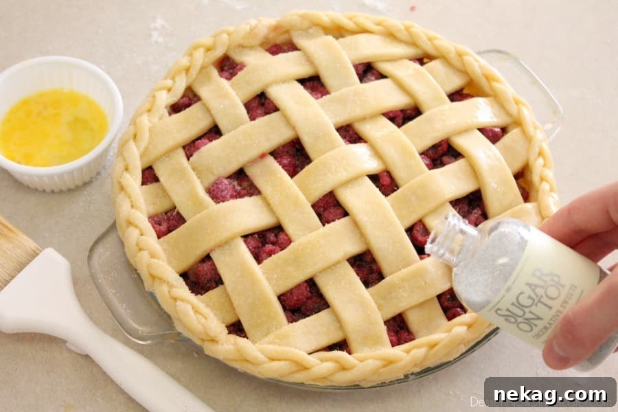 Granulated sugar being sprinkled over the egg-washed lattice pie crust, adding sweetness and sparkle before baking.
