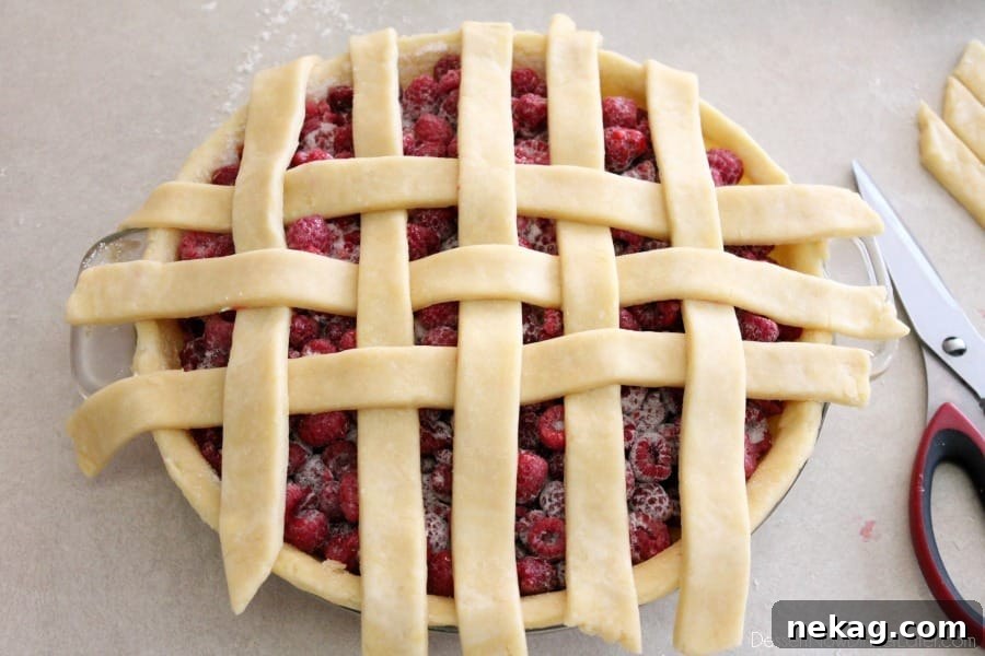 More vertical pie crust strips being woven into the lattice, demonstrating the alternating over-and-under pattern with horizontal strips.