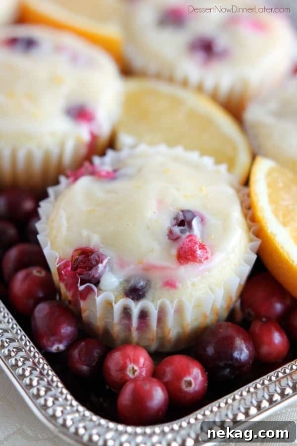 A batch of golden-brown Cranberry Orange Muffins cooling on a wire rack, ready to be glazed, highlighting their appetizing appearance.