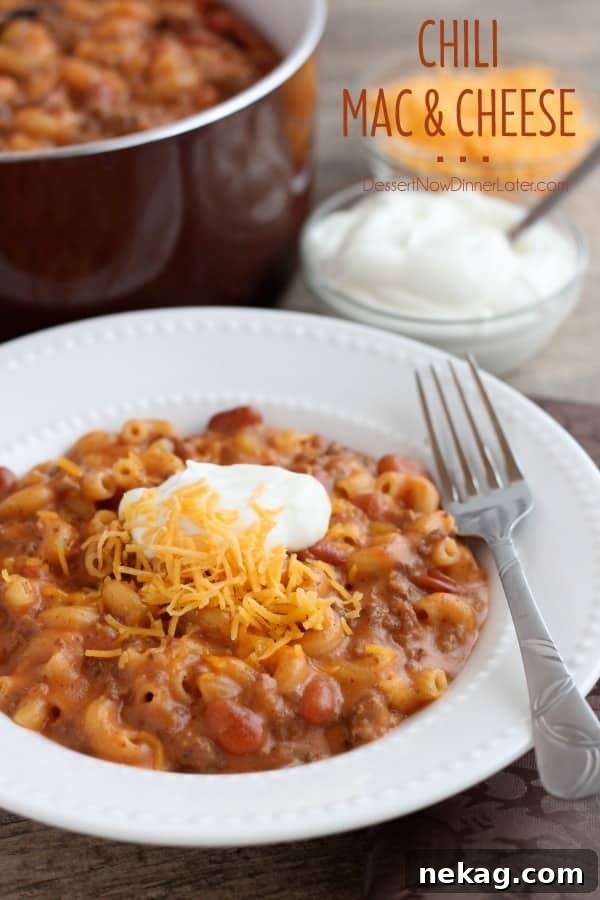 A hearty bowl of homemade Chili Mac and Cheese, topped with a dollop of sour cream and fresh herbs, ready to be enjoyed as a comforting meal.
