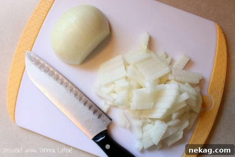 Fresh Frozen Staples 5 Diced onion pieces laid out on a cutting board, ready to be frozen or transferred to a freezer bag.