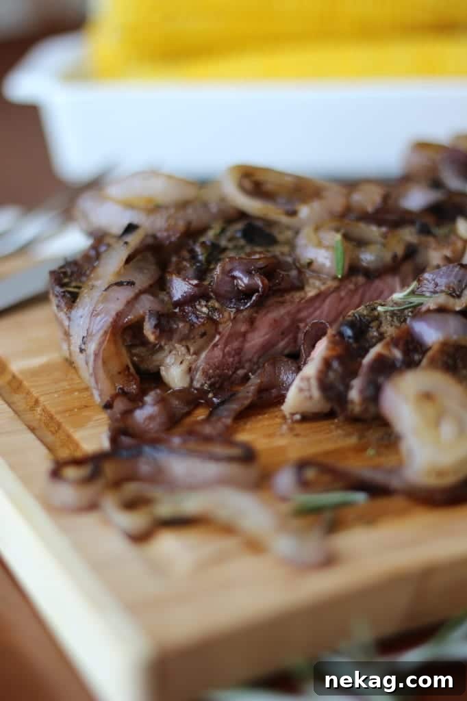 A close-up shot of the cooked rib-eye steak, perfectly seared and resting on a wooden cutting board.