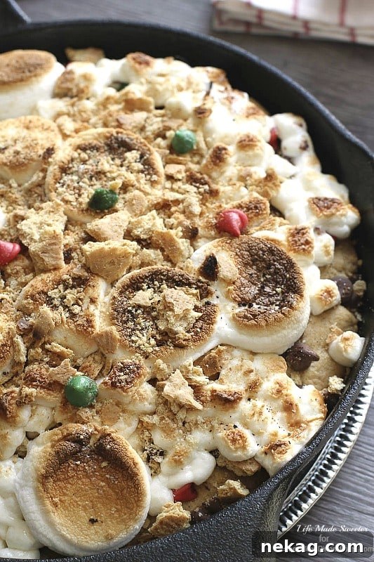 A slice of Gingerbread S'mores Cookie Pizza, showcasing gooey marshmallows and melted chocolate chips.