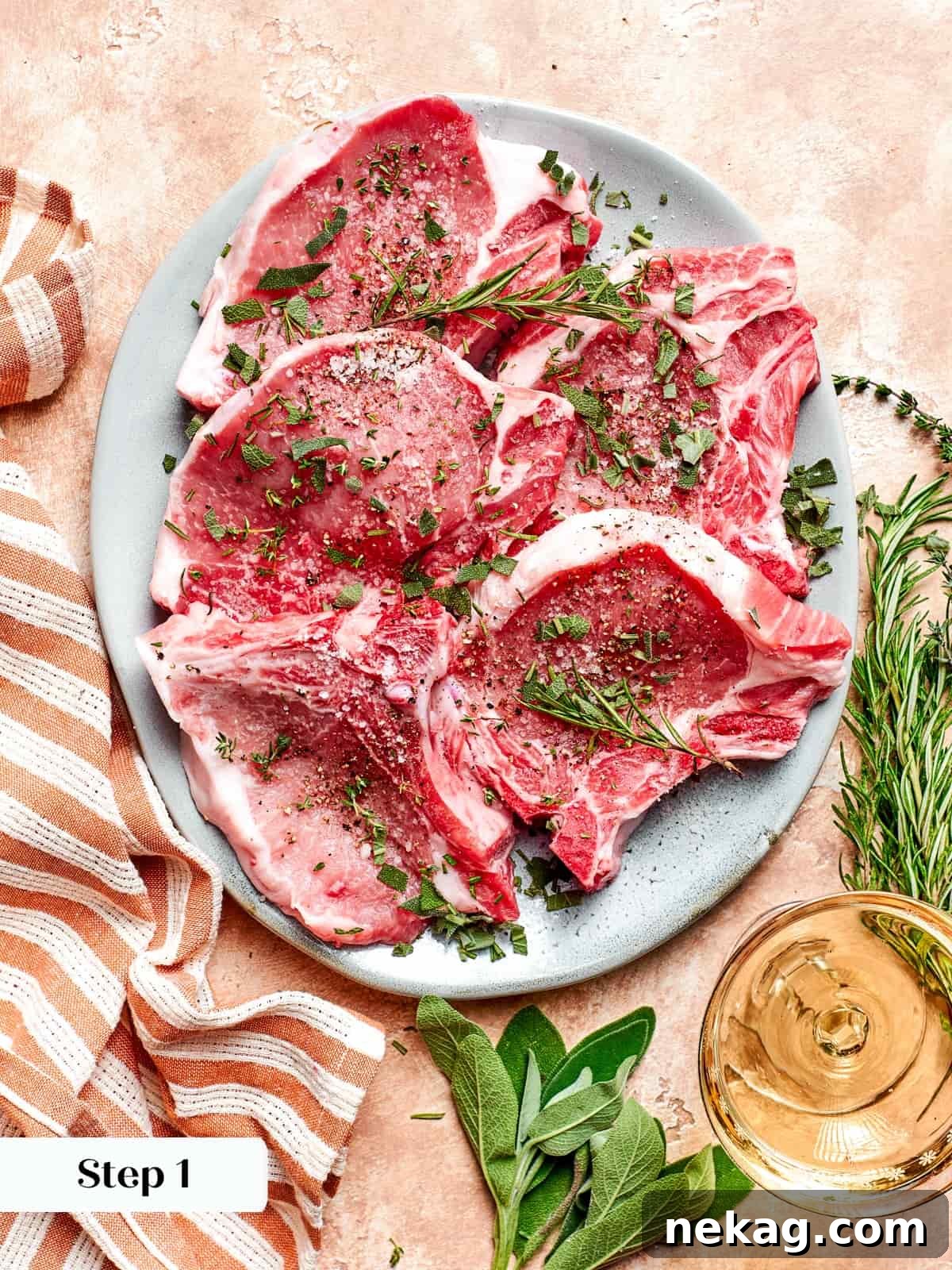 Raw pork chops seasoned with salt, pepper, and chopped fresh herbs.