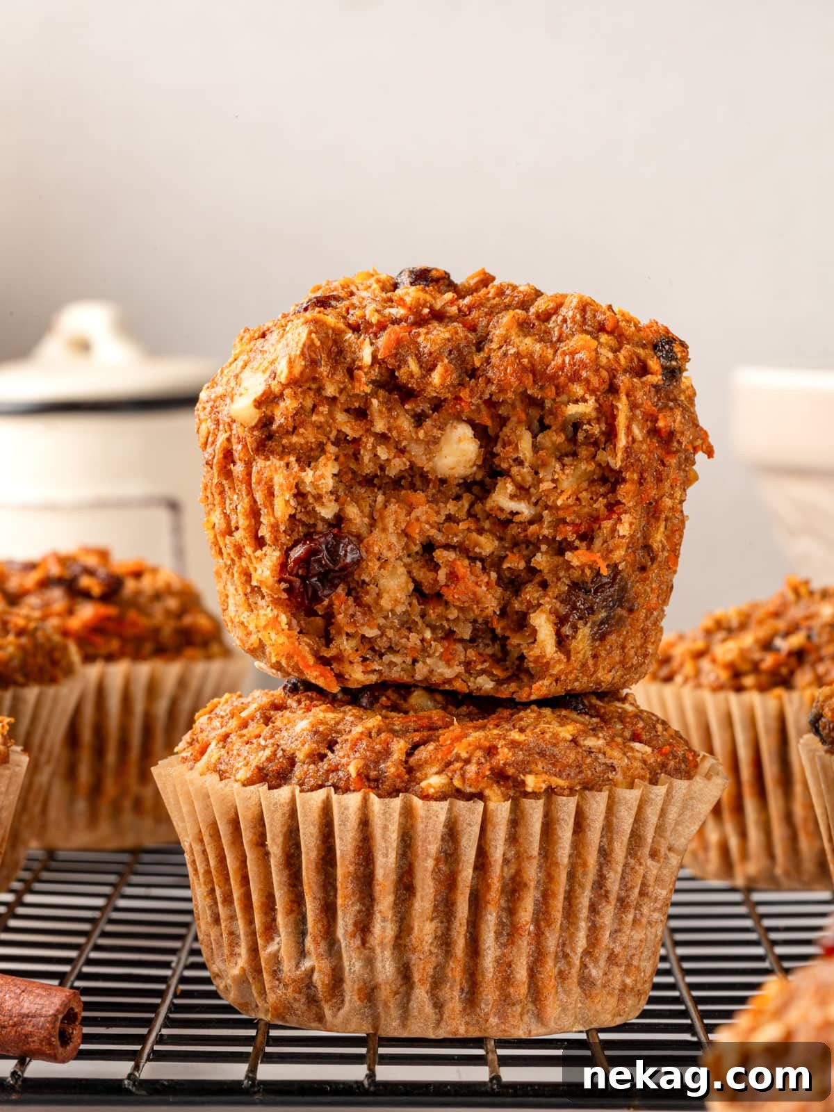 A perfectly baked, wholesome morning glory muffin, bitten to reveal its fluffy interior filled with tender carrots, hearty oats, and juicy raisins.