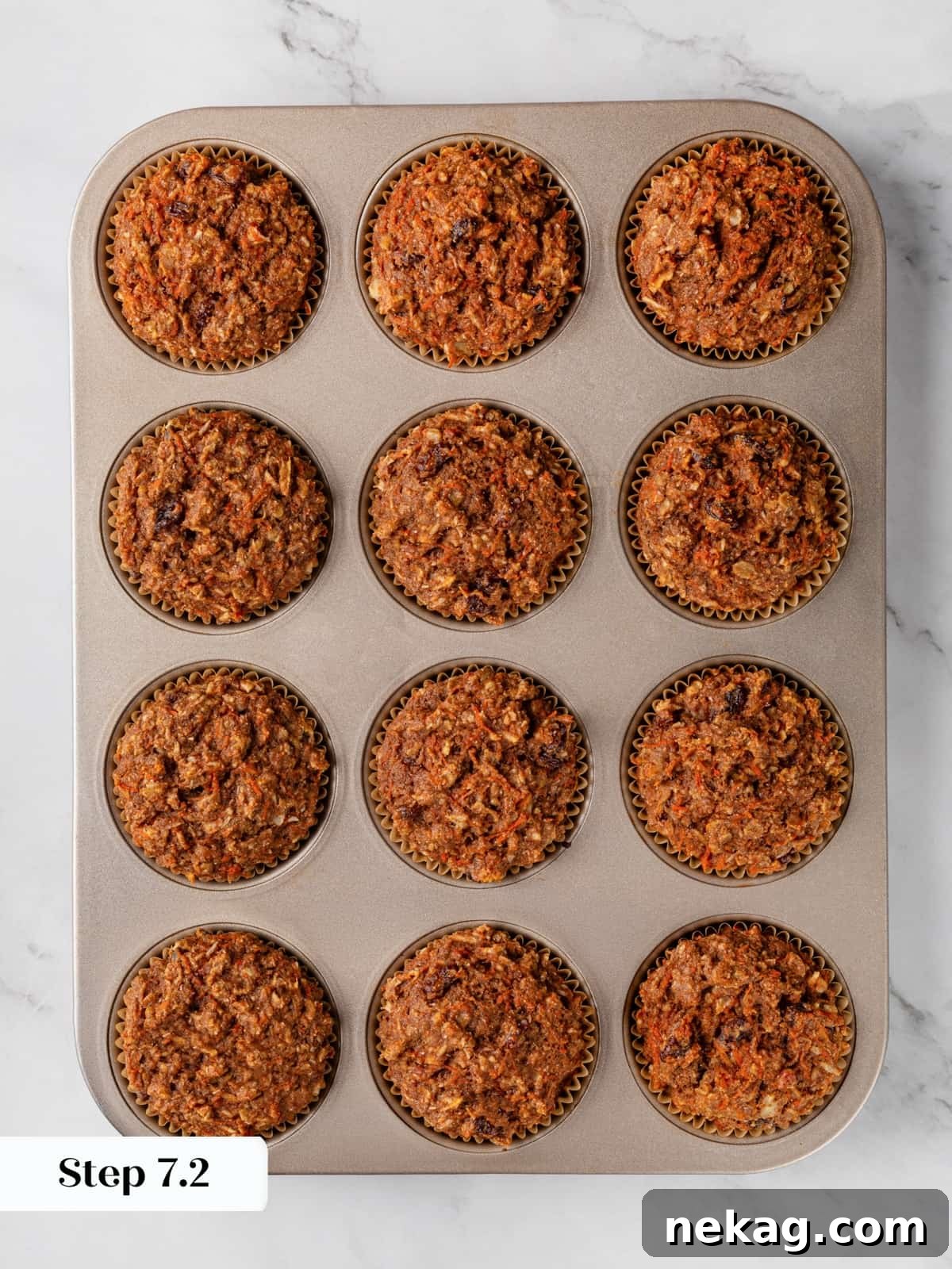 Golden-brown morning glory muffins, perfectly baked, cooling in their muffin pan after being removed from the oven.