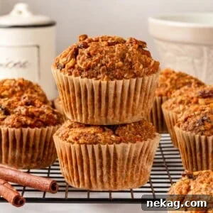 A stack of golden-brown whole grain morning glory muffins, accompanied by fragrant cinnamon sticks, ready to be enjoyed.