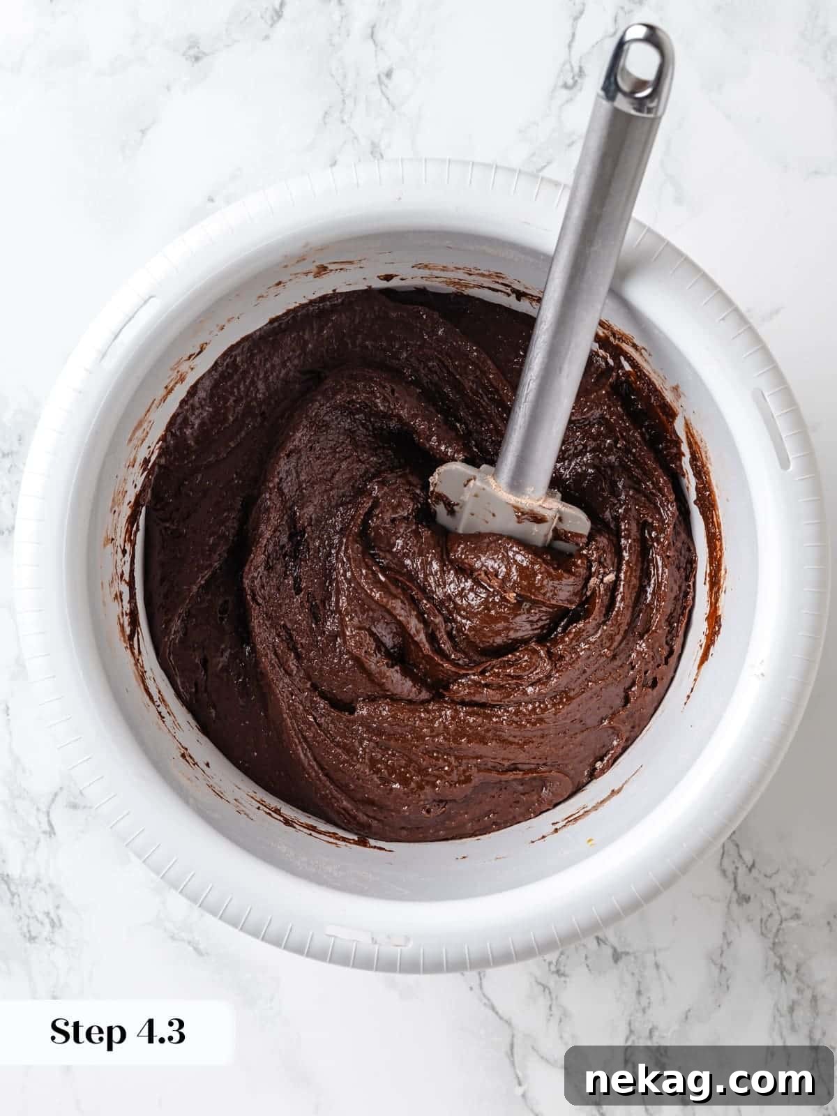 Dry ingredients gently folded into wet chocolate cake batter using a silicone spatula to avoid overmixing.