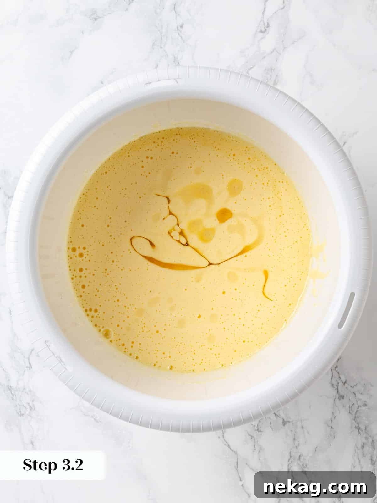 Vegetable oil poured slowly into mixing bowl with eggs and sugar for chocolate cake, creating an emulsion.