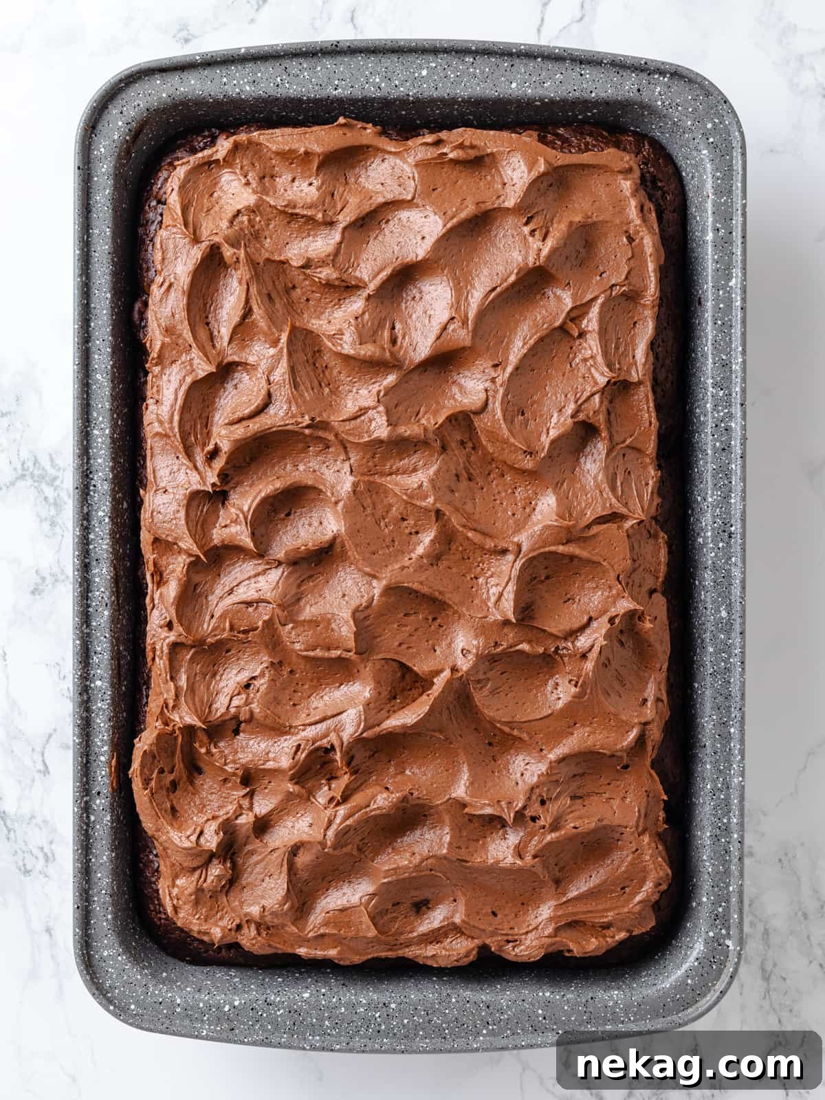 Silky chocolate cream cheese frosting spread, showcasing soft waves and a smooth, luxurious texture.