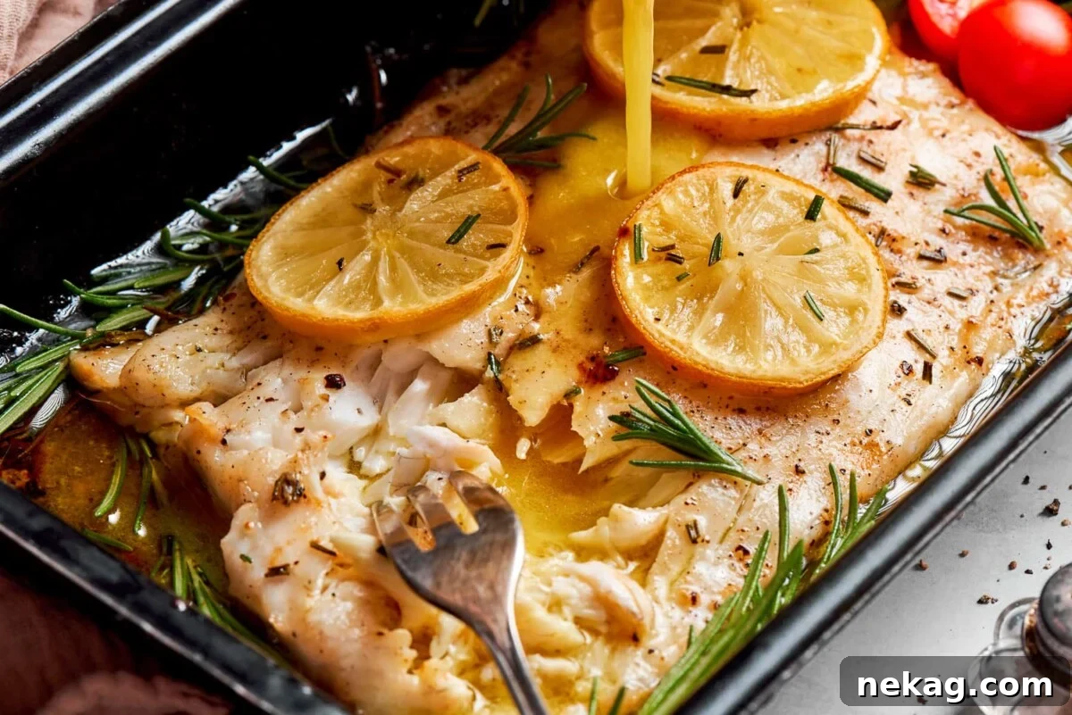 Champagne vinaigrette generously poured over perfectly baked halibut with fresh lemon slices on a baking pan.