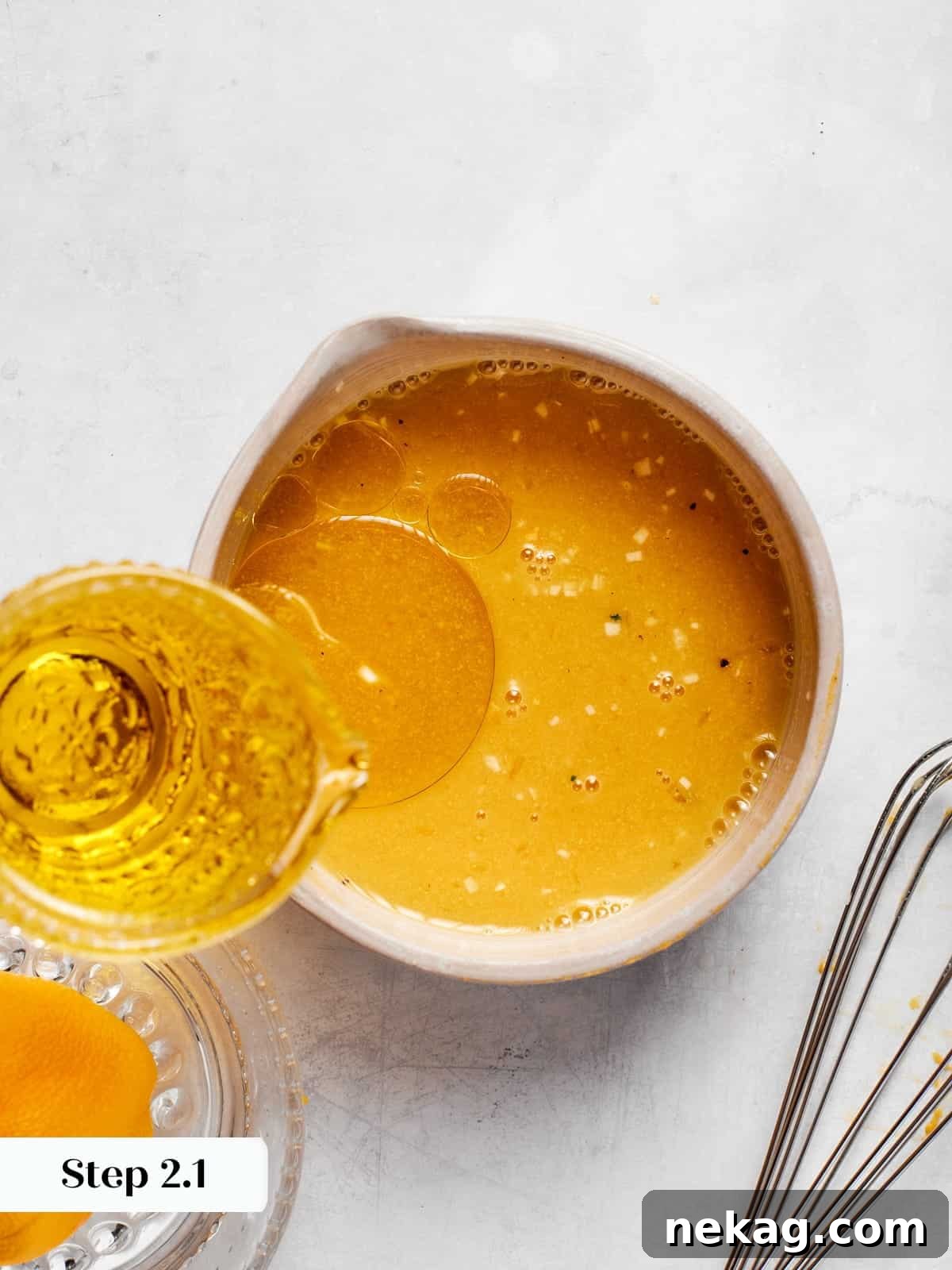 Olive oil slowly poured into champagne vinaigrette mixture while continuously whisking to combine.