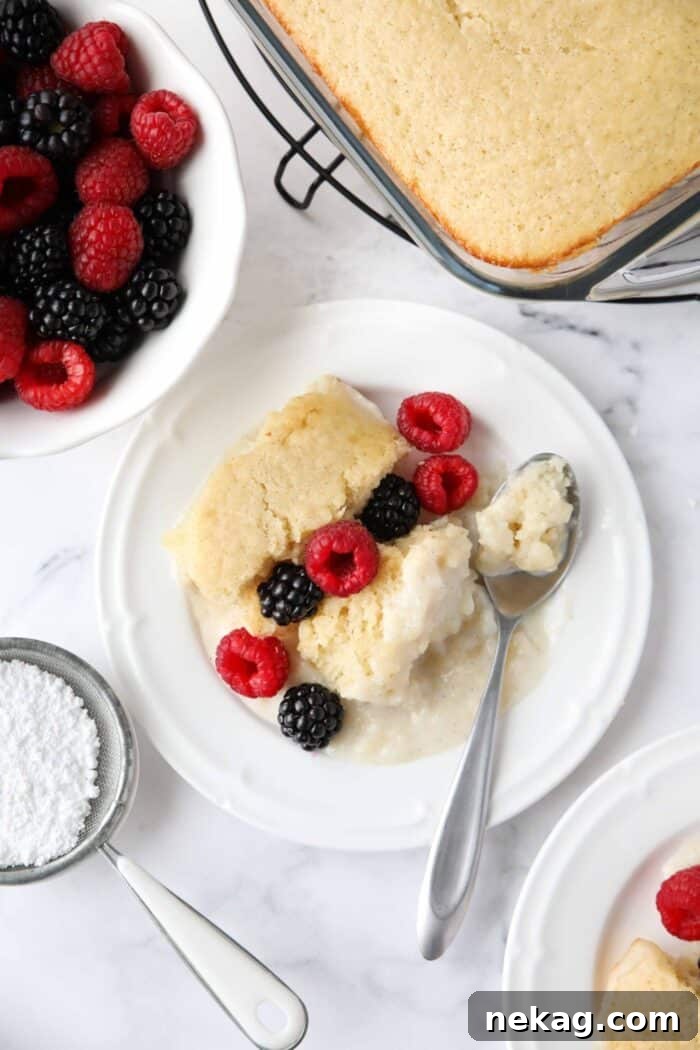 A serving of vanilla pudding cake on a plate, garnished with a medley of fresh berries, ready to be enjoyed.