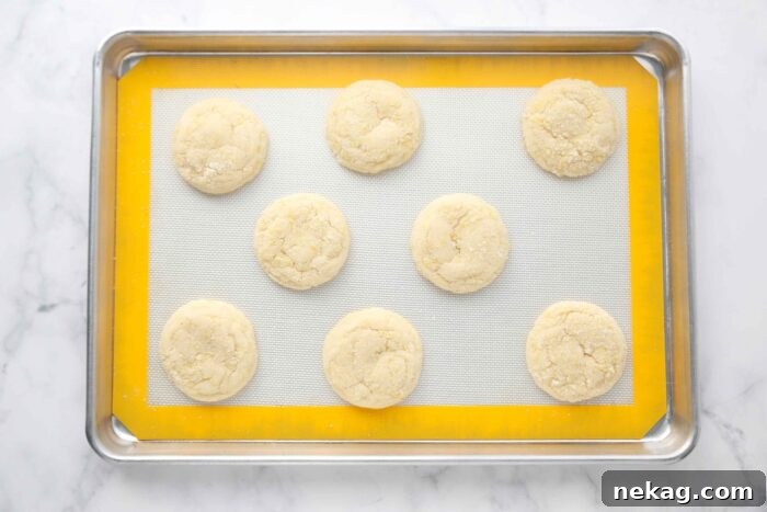 Zesty Lemon Cookie Delight 6 Freshly baked lemon cookies on a baking sheet tray, ready to be cooled.