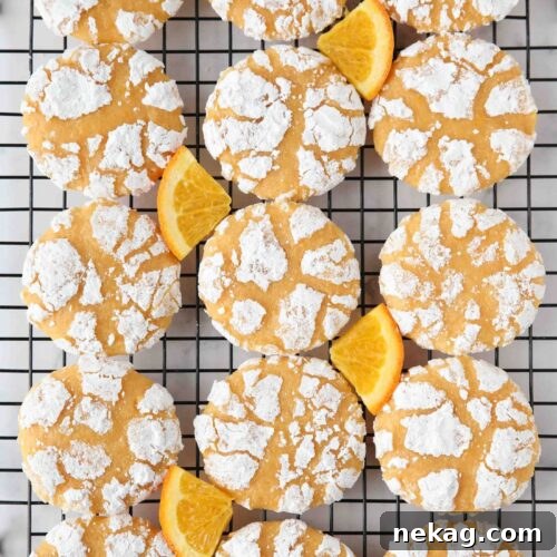 Orange crinkle cookies on a wire cooling rack with orange slices.