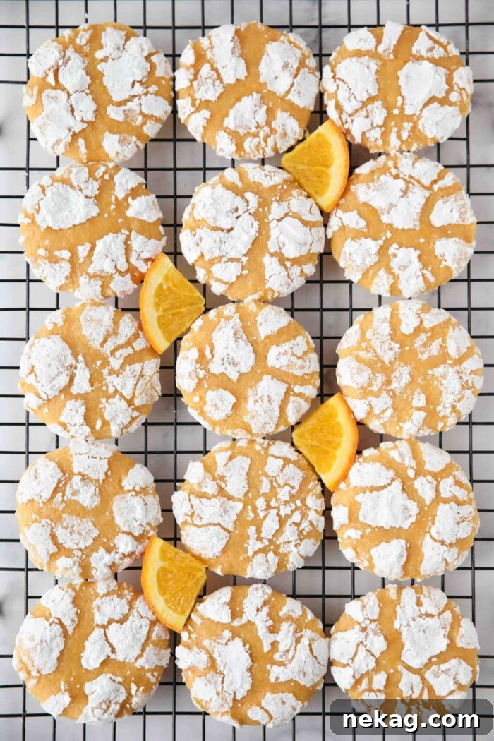Orange crinkle cookies on a wire cooling rack with orange slices.