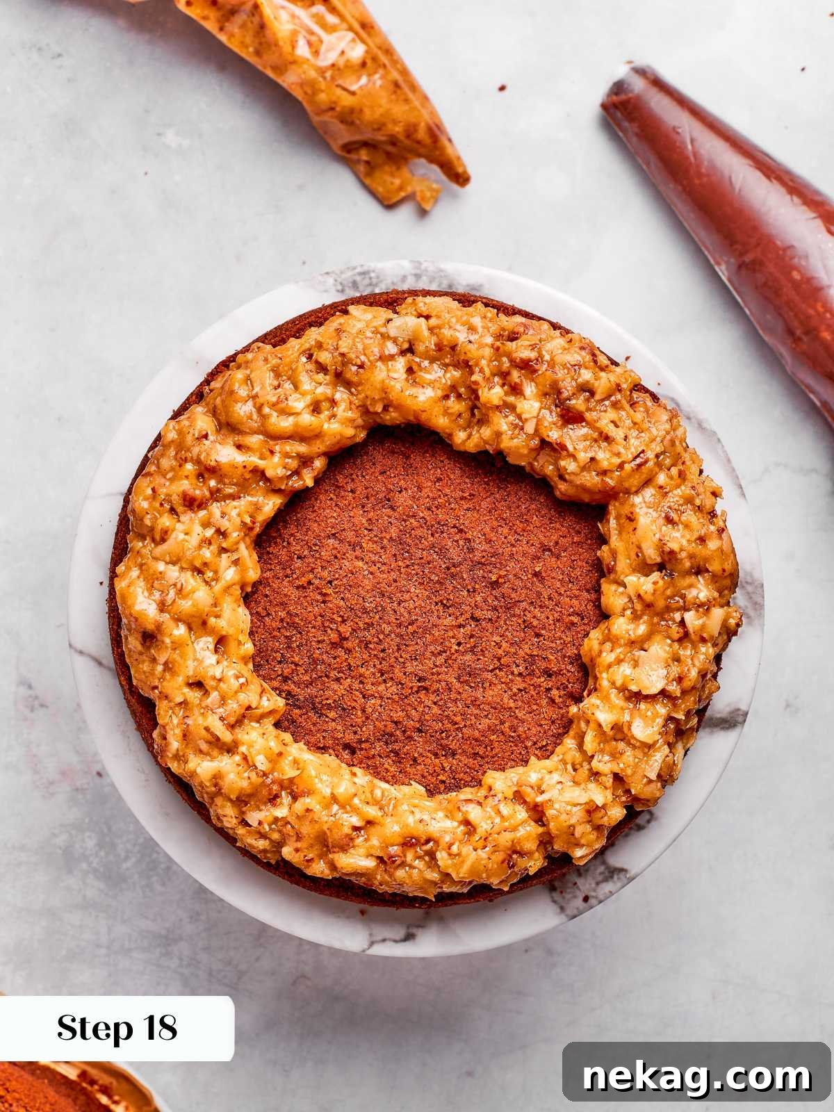 Ring of coconut pecan frosting piped around cake edge to hold ganache filling.