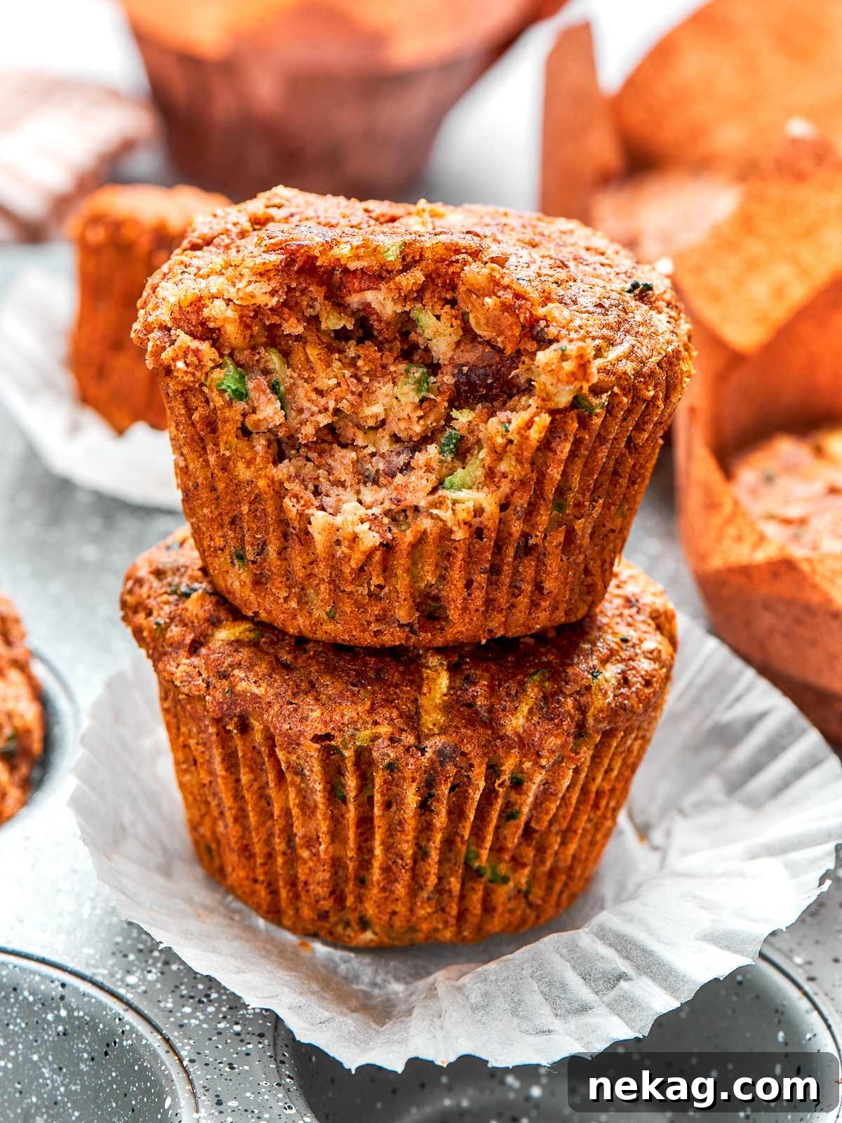 Stack of zucchini muffins with golden tops and tender crumb.