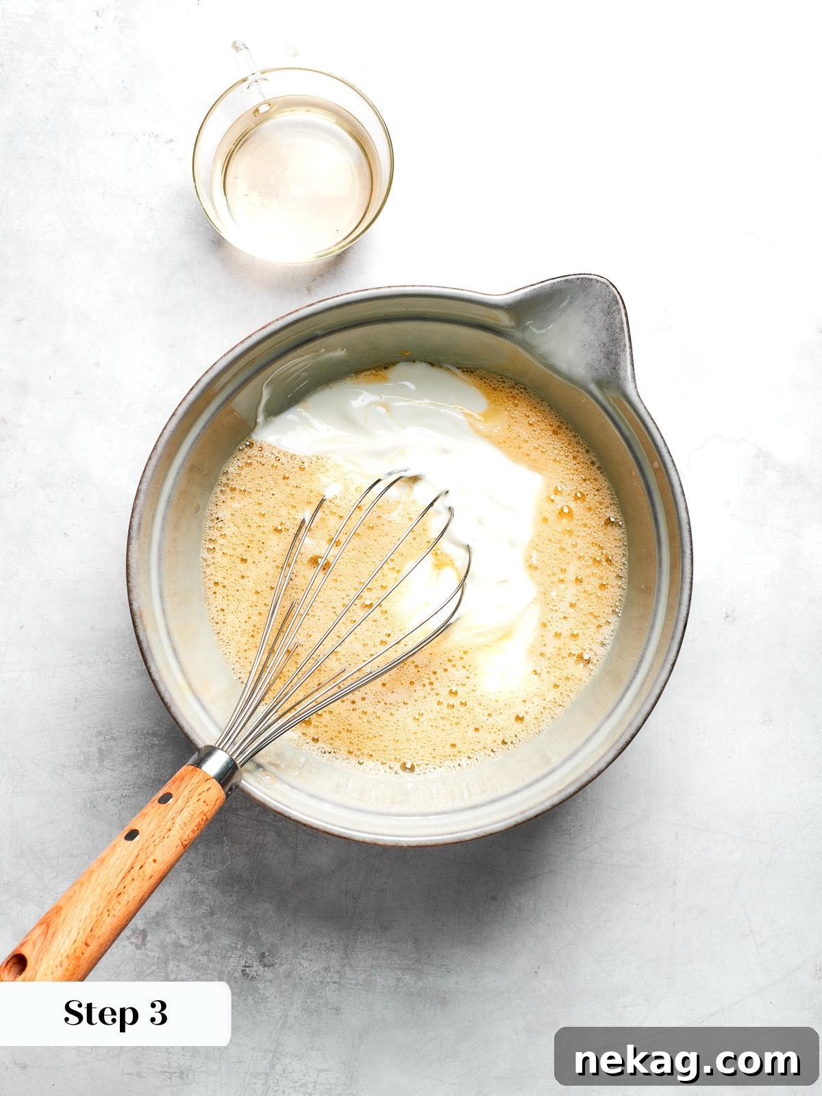 Wet ingredients including yogurt maple syrup and egg whisked together for muffin batter.