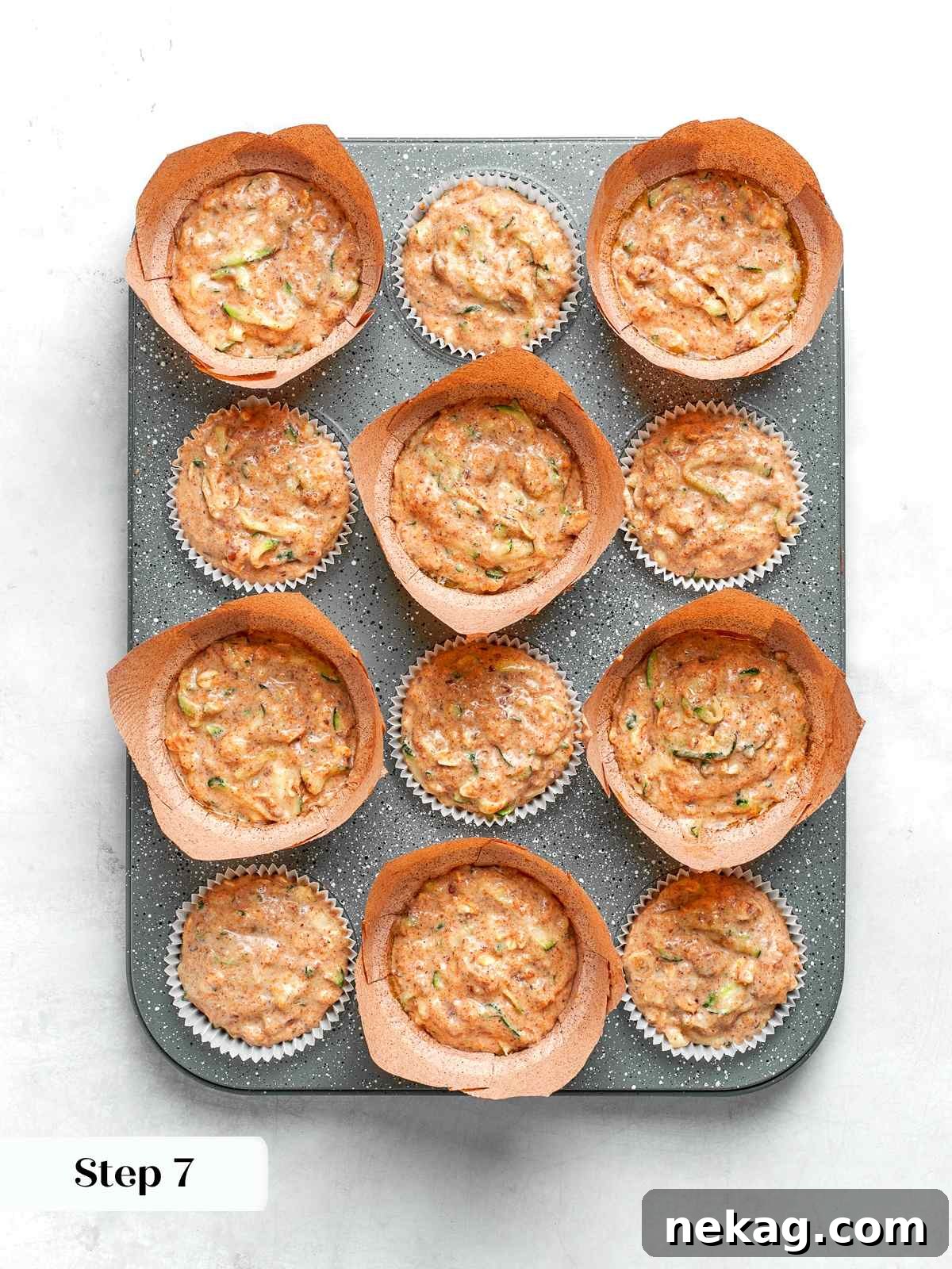 Zucchini muffin batter scooped into lined muffin cups ready for baking.