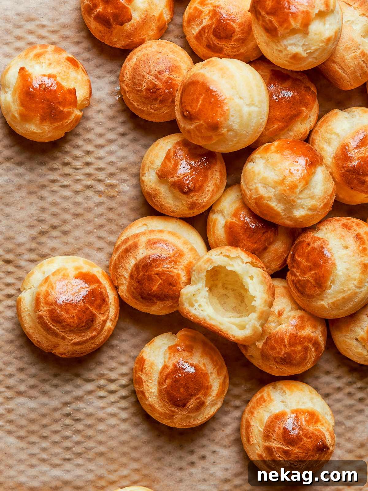 Tray of baked choux pastries with consistent puffing and evenly browned crisp shells.
