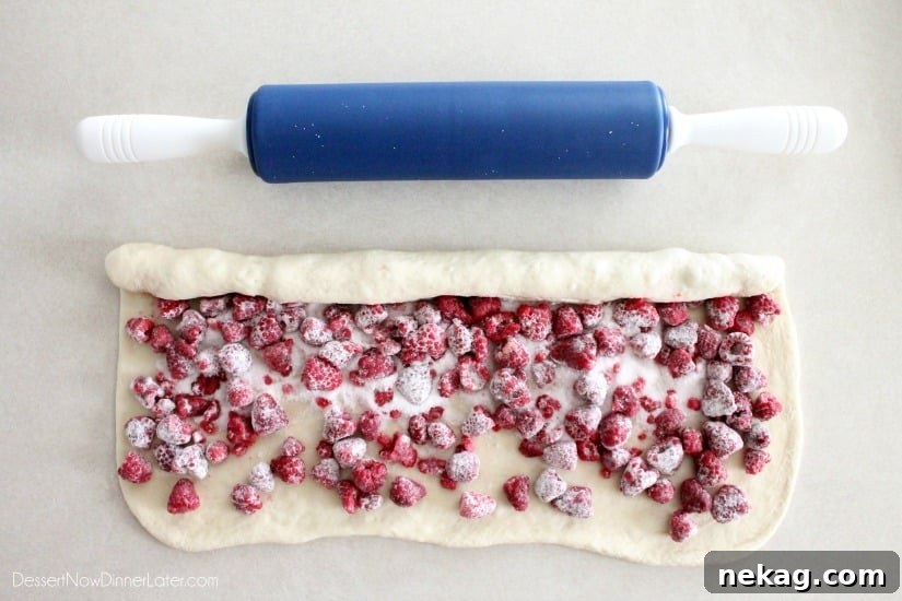 Rolling top edge of the dough over the berries, and stopping in the center.