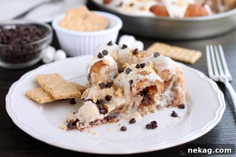 Crushed graham crackers, mini chocolate chips, and mini marshmallows are rolled up in buttery cinnamon sugar rolls to create this S'mores Cinnamon Roll Cake. Top it all off with a marshmallow frosting and extra toppings for a delicious dessert!