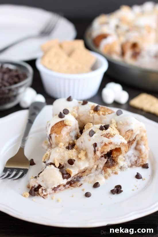 Crushed graham crackers, mini chocolate chips, and mini marshmallows are rolled up in buttery cinnamon sugar rolls to create this S'mores Cinnamon Roll Cake. Top it all off with a marshmallow frosting and extra toppings for a delicious dessert!