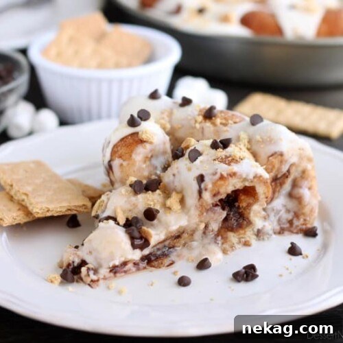 Crushed graham crackers, mini chocolate chips, and mini marshmallows are rolled up in buttery cinnamon sugar rolls to create this S'mores Cinnamon Roll Cake. Top it all off with a marshmallow frosting and extra toppings for a delicious dessert!