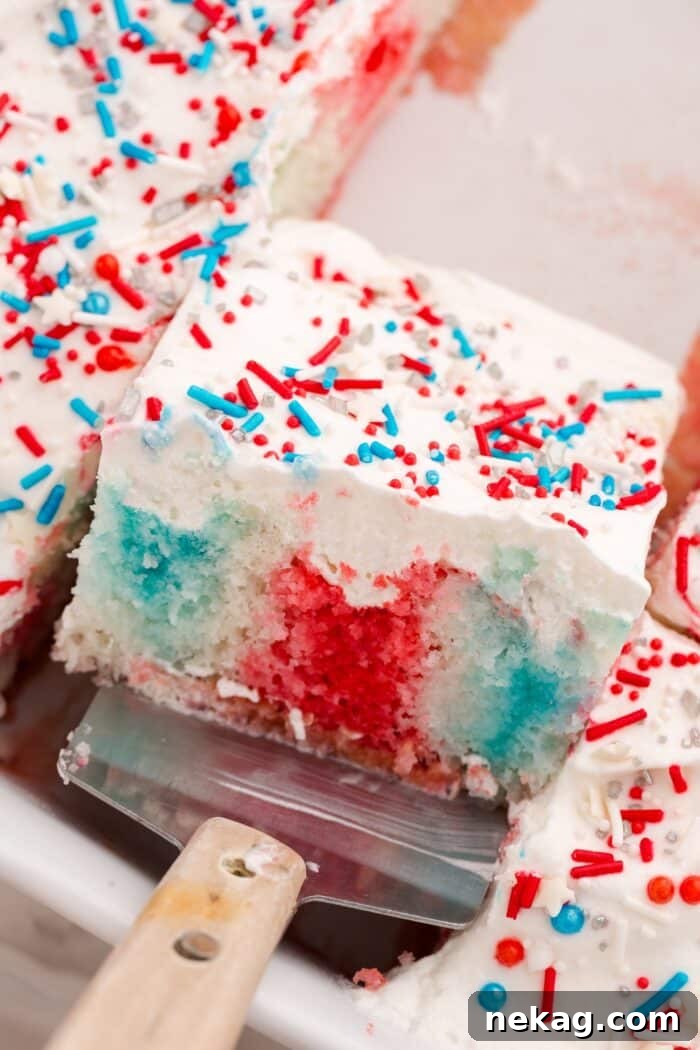 Red white and blue jello poke cake in a pan with a scoop.