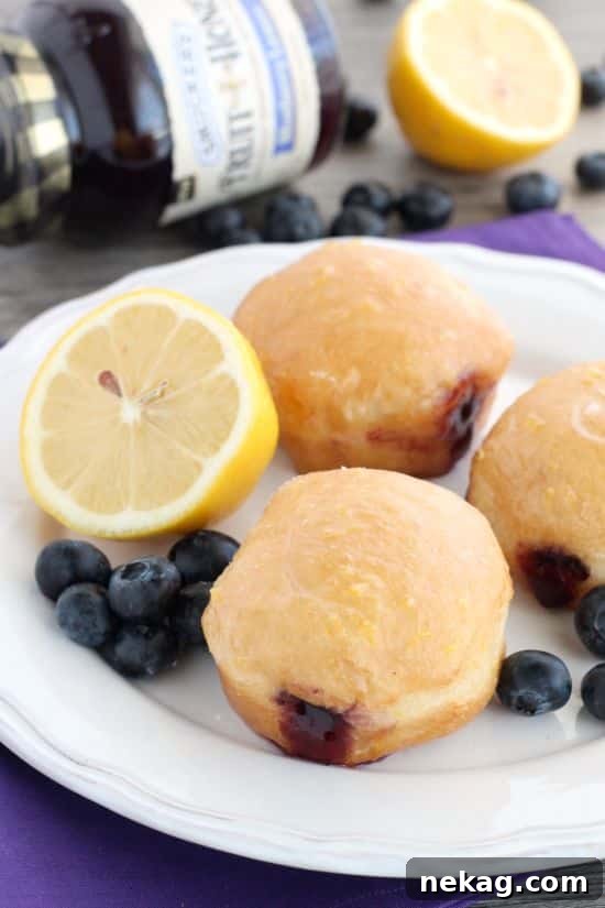 These Jelly Filled Mini Donuts make the perfect breakfast or dessert! Lemon glazed donuts are made easy with refrigerated biscuit dough, and are stuffed with a naturally sweetened blueberry lemon fruit spread.