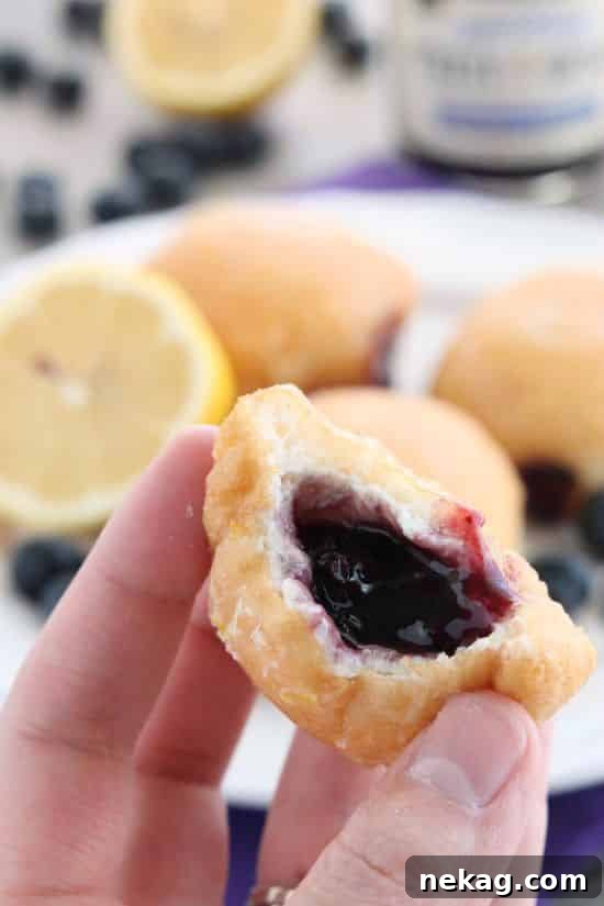 These Jelly Filled Mini Donuts make the perfect breakfast or dessert! Lemon glazed donuts are made easy with refrigerated biscuit dough, and are stuffed with a naturally sweetened blueberry lemon fruit spread.