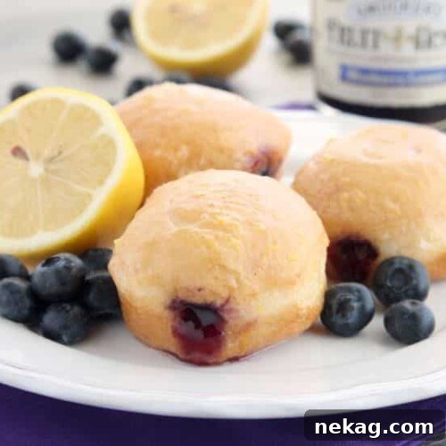 These Jelly Filled Mini Donuts make the perfect breakfast or dessert! Lemon glazed donuts are made easy with refrigerated biscuit dough, and are stuffed with a naturally sweetened blueberry lemon fruit spread.
