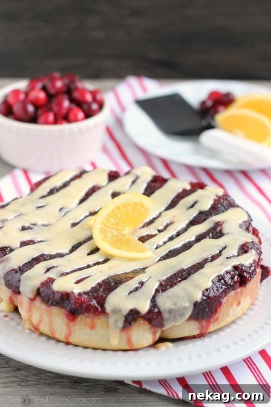 Frozen orange rolls are baked atop fresh cranberry sauce, inverted onto a dish, and drizzled with a delicious orange cream cheese glaze for a Christmas breakfast worth sharing with family and friends.