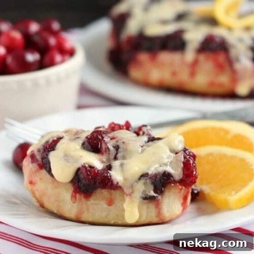 Frozen orange rolls are baked atop fresh cranberry sauce, inverted onto a dish, and drizzled with a delicious orange cream cheese glaze for a Christmas breakfast worth sharing with family and friends.