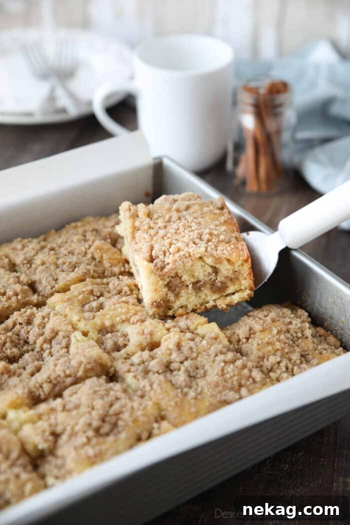 Moist Sour Cream Coffee Cake Recipe with Cinnamon Streusel 3 Scooping a piece of sour cream coffee cake out of the pan.
