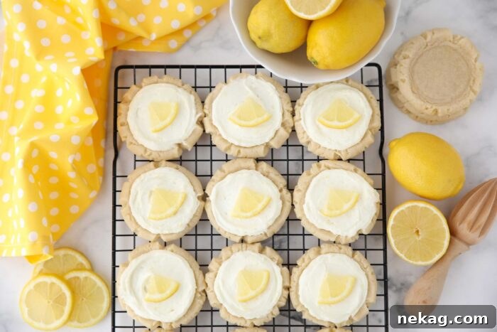 Frosted lemon sugar cookies with lemon slices on a wire cooling rack.