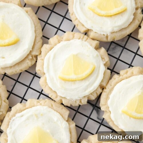 Close up of lemon sugar cookies with lemon frosting and a slice of lemon on top.