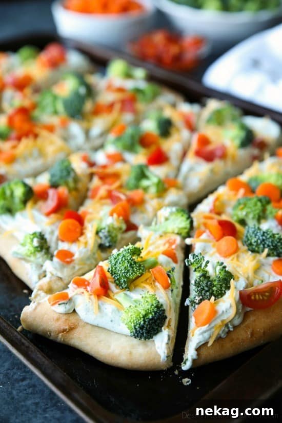 Cold vegetable pizza topped with cherry tomatoes, broccoli, and shredded cheese