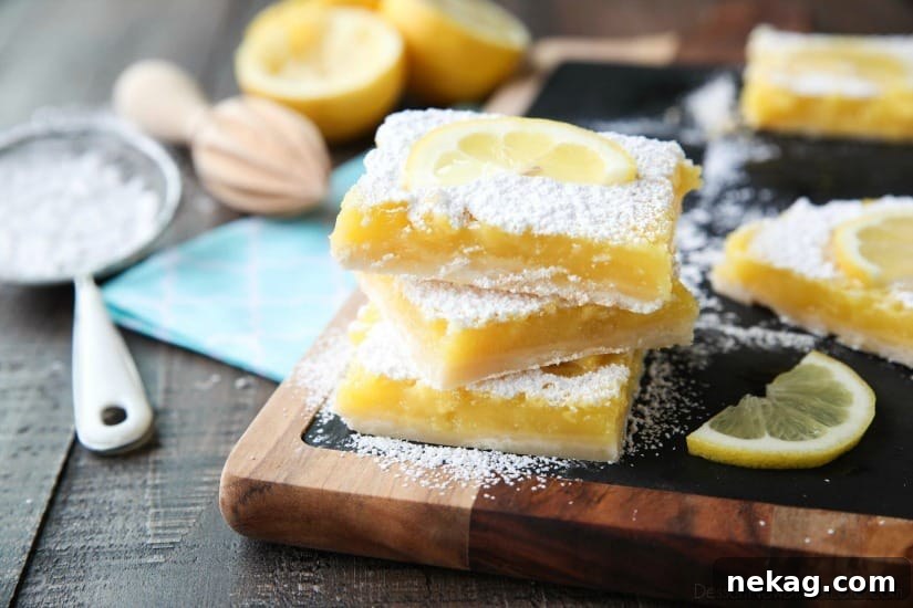 Zesty Lemon Bars Recipe: Tangy Shortbread Squares 4 Three lemon bars stacked with powdered sugar and a lemon slice on top.