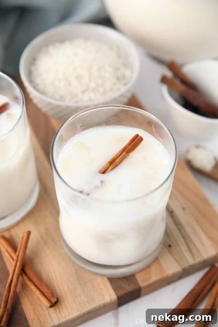 Horchata Recipe with Video Tutorial 2 Close-up view of Mexican horchata in a cup with ice and a cinnamon stick.