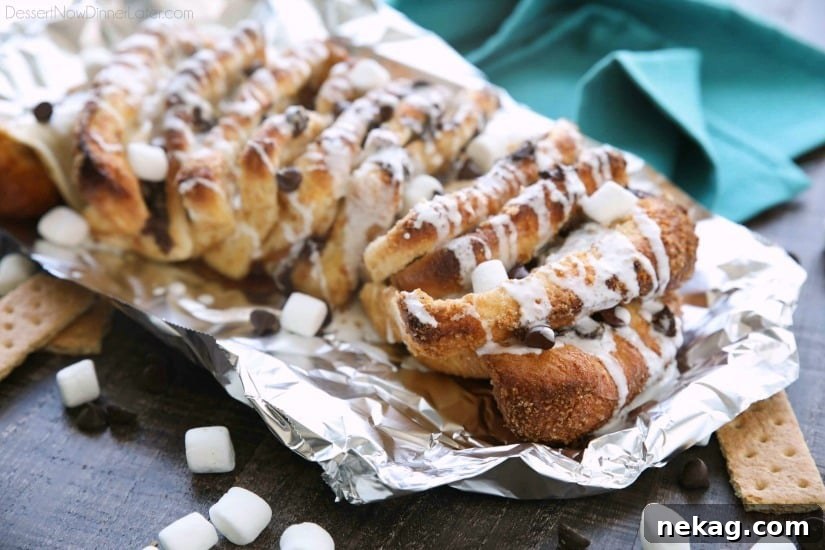 S'mores Pull Apart Bread is loaded with graham cracker crumbs, marshmallows, and chocolate chips, then topped off with a marshmallow glaze for a camping inspired dessert you can enjoy anytime!