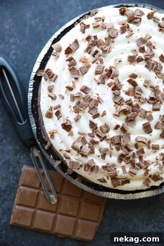 A layered no-bake cheesecake chilled and ready to serve with whipped cream and chocolate shavings.