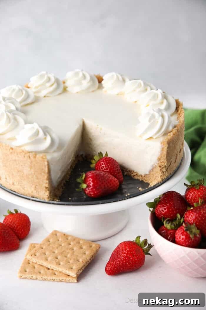 No bake cheesecake on a cake plate with a couple slices taken out and fresh strawberries on the side.