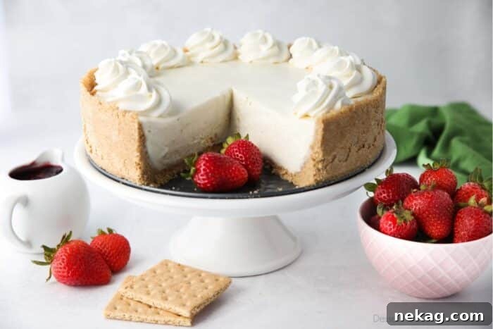 No bake cheesecake on a cake plate with a couple slices taken out and fresh strawberries on the side.