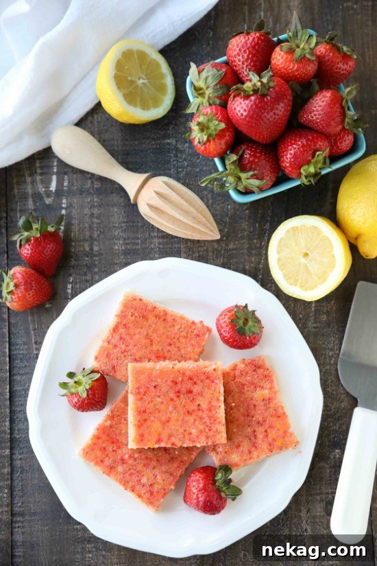 Squares of strawberry and lemon bars on plate with fresh strawberries.