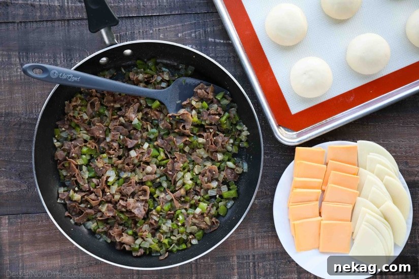 Philly Cheesesteak Bombs: Loaded Steak, Cheese & Onion Bites 6 Skillet with cooked meat and vegetables next to a plate of sliced cheese.
