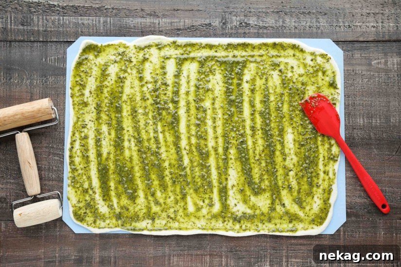 Crispy Pesto Breadsticks Recipe for Garlic-Parmesan Dipping 6 Rhodes bread dough rolled into a rectangle with pesto spread on top.